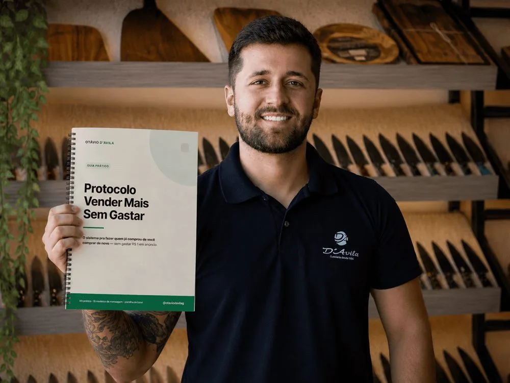 Otavio segurando o guia Protocolo Vender Mais Sem Gastar na cutelaria